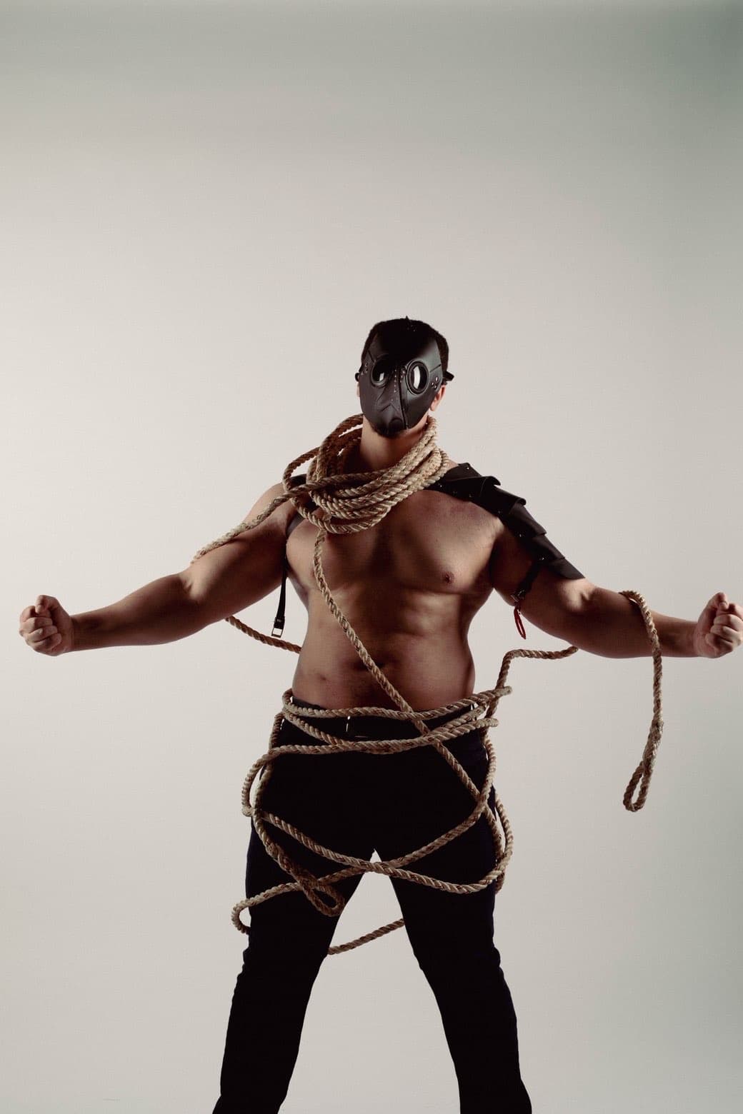 Masked studio portrait with rope wrapped around torso